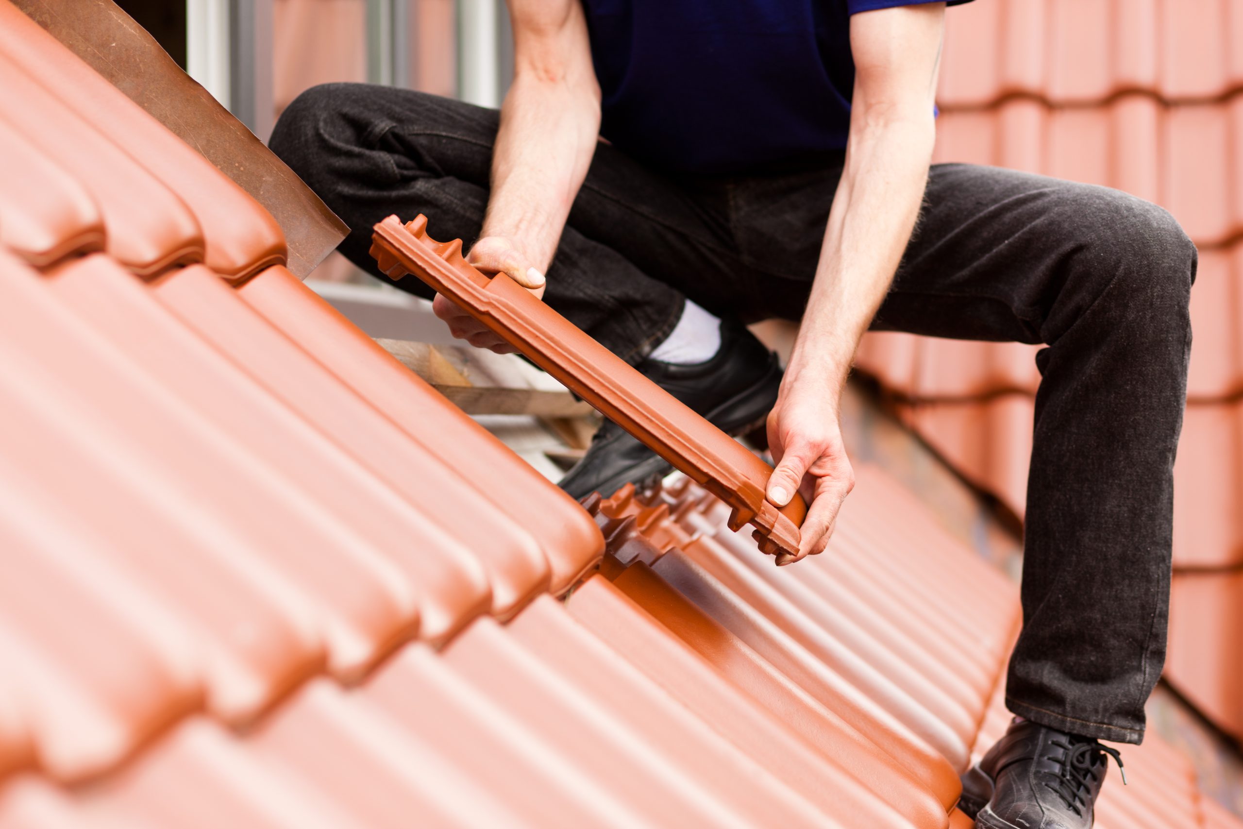 Roofing - construction worker standing on a roof covering it with tiles